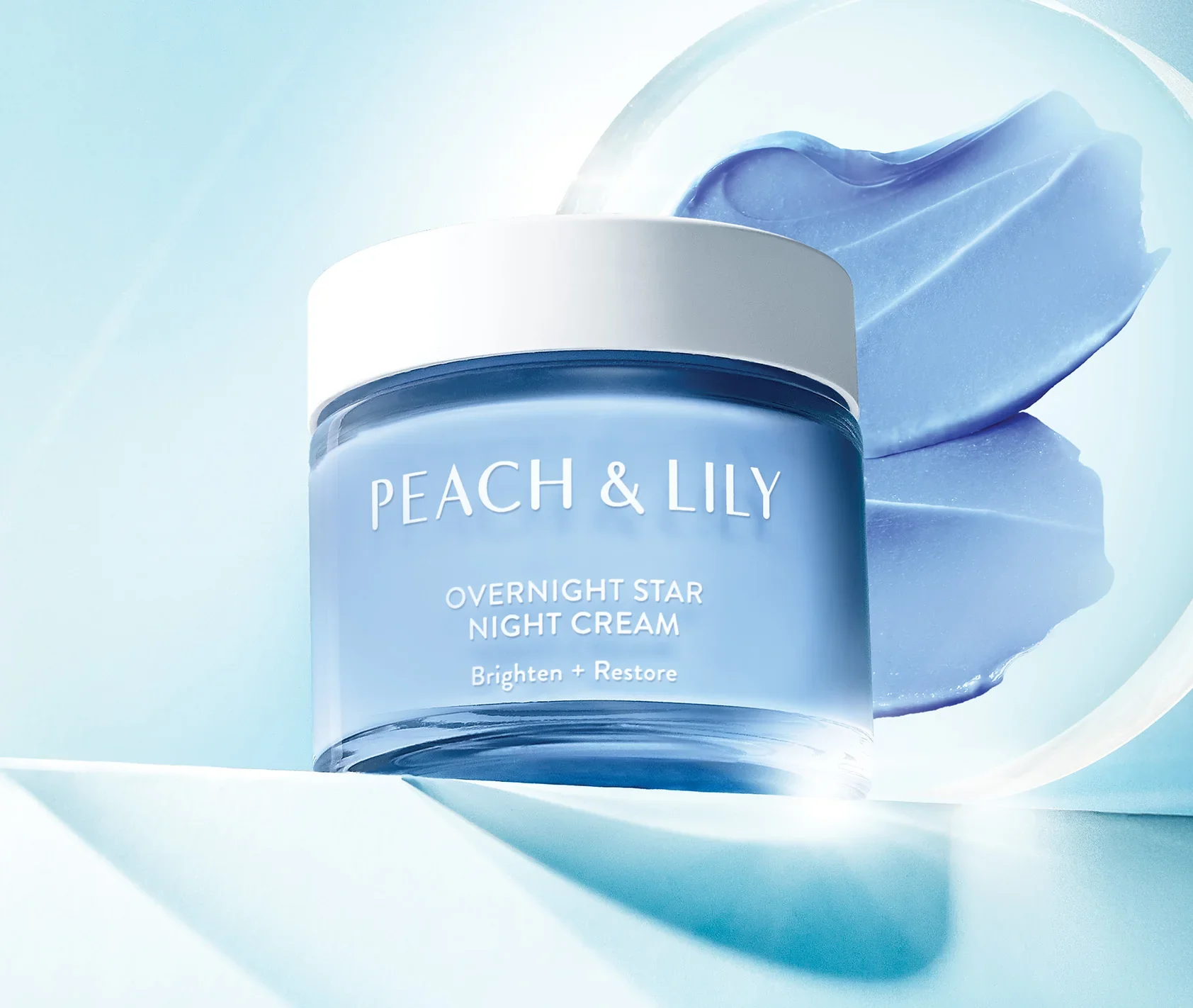 Peach & Lily Overnight Star Night Cream in a blue jar on a blue background with cream swirls.